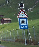 Sign warning of a tunnel and traffic lights in Switzerland.