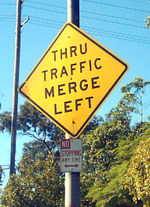 A U.S. warning sign indicating that drivers who do not wish to exit immediately should merge left, and a prohibitory No Stopping sign