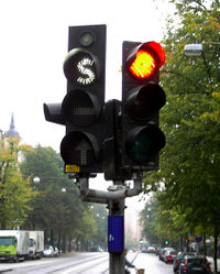 Swedish traffic light (left) for use by public transport vehicles only. All signals use white lighting and special symbols ("S", "" and an arrow) to distinguish them from regular signals. The small light at the top tells the driver when the vehicles transponder signal is received by the traffic light.