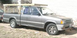 Mazda compact Pickup truck with extended cabin and homebuilt lumber rack.