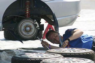 A mechanic works on the rear end of a car