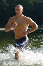 U.S. Marine emerges from the water upon completing the swimming portion of a triathlon.