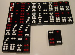 A set of Chinese dominoes. The top double-row of tiles lists the eleven matching pairs, in descending value from left to right. Below them are five non-matching pairs, worth less than the matching pairs, and also in descending value from left to right. The Gee Joon tiles, lower right, are the highest pair of all.