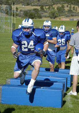 A halfback leads fellow backs through an agility drill