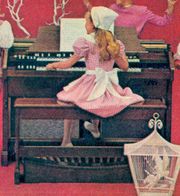 A typical console organ of the early 1960s.  Considerably larger and more imposing than the spinet, it resembles the console of a pipe organ (yet this advertisement makes a point of emphasizing that even children are capable of mastering it, as the girl here is demonstrating). Note the five-octave in-line manuals, the extra drawbars, and the full pedalboard, all of which make this a more complex, but also a more powerful and flexible, instrument than the spinet.