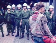 A punk faces a line of riot police.