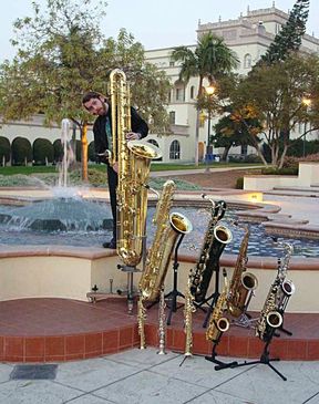 Jay C. Easton with ten members of the saxophone family. From largest to smallest: contrabass, bass, baritone, tenor, C melody, alto, F mezzo-soprano, soprano, C soprano, sopranino.