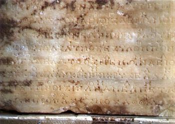 Photograph of the original stone at Delphi containing the second of the two hymns to Apollo.  The music notation is the line of occasional symbols above the main, uninterrupted line of Greek lettering.